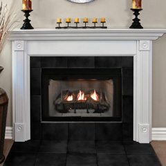 A lit fireplace with a white mantel and framing moulding with plinth rosettes and blocks